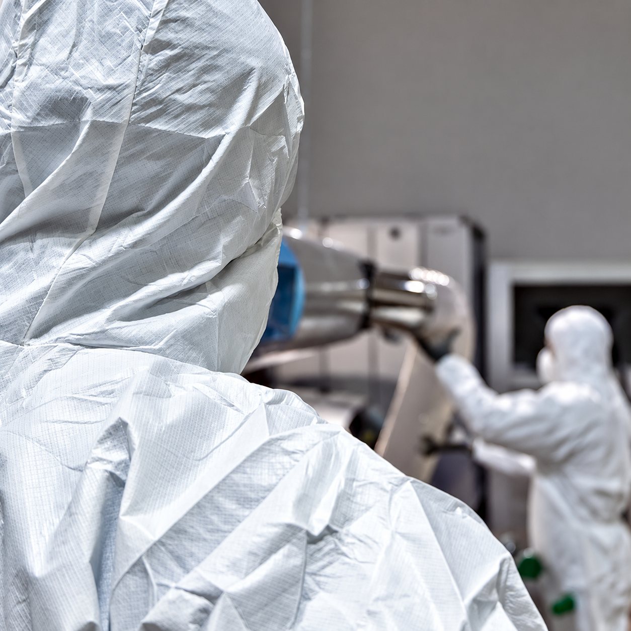 Techniciens en combinaison blanche intervenant sur un conduit de ventilation